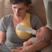 Yellow flexible baby bottle support holder with an ergonomic strap-free design, measuring 48 × 16 × 13 cm or 18.9 × 6.3 × 5.1 inches.