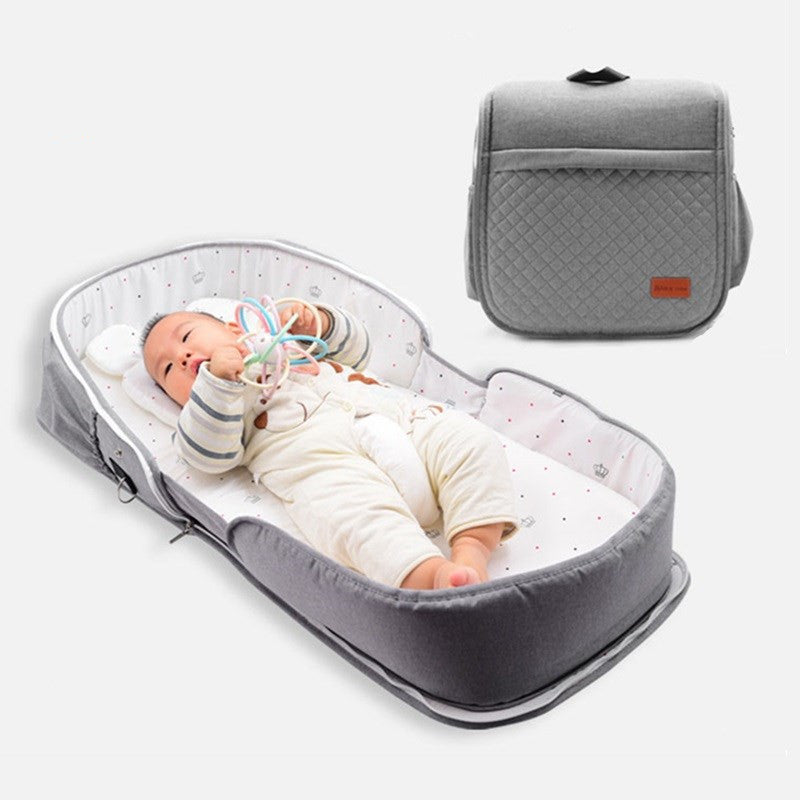 Foldable portable newborn baby crib with a mosquito net, cotton pad and compact backpack-style design.
