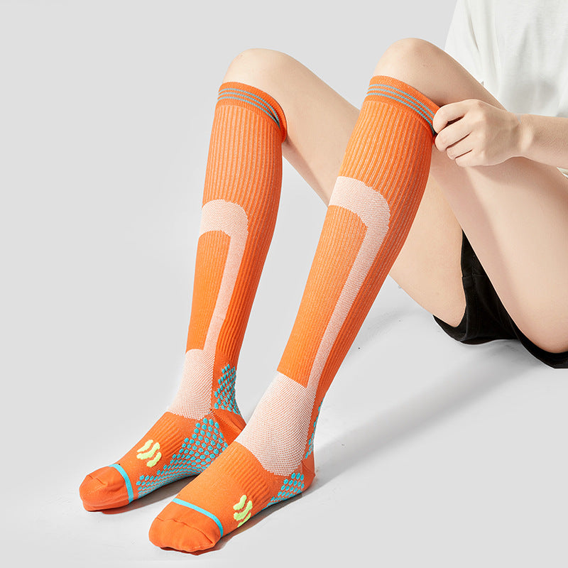Person wearing orange high-tube professional sports calf socks with reinforced heel, ankle and foot zones