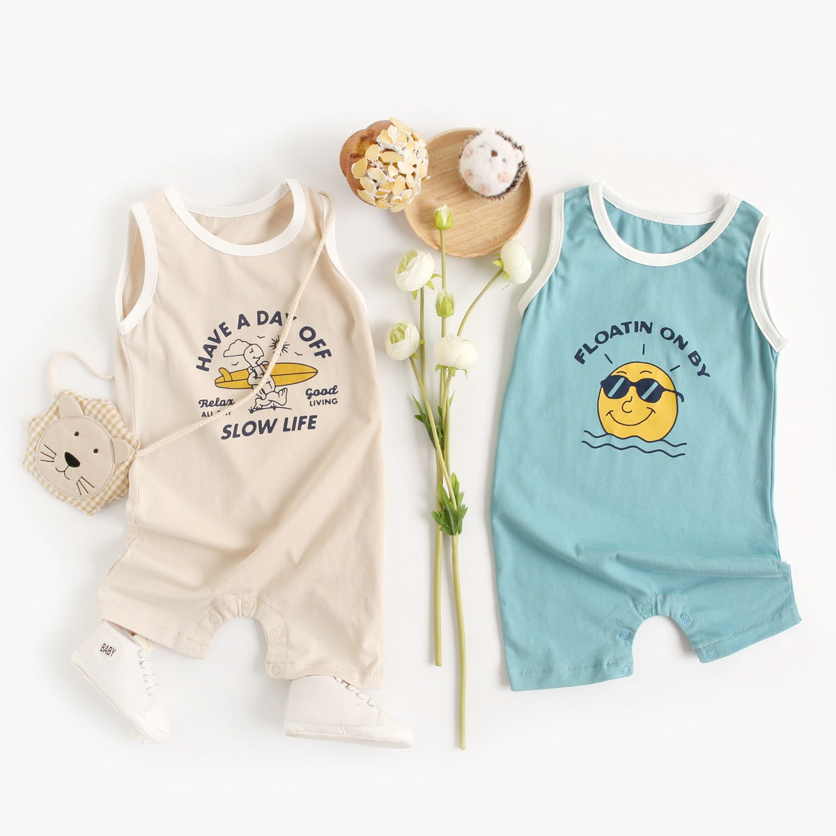 Sleeveless cotton baby jumpsuit available in blue sun and khaki surfboard prints for children aged 0–6 months to 2–3 years.