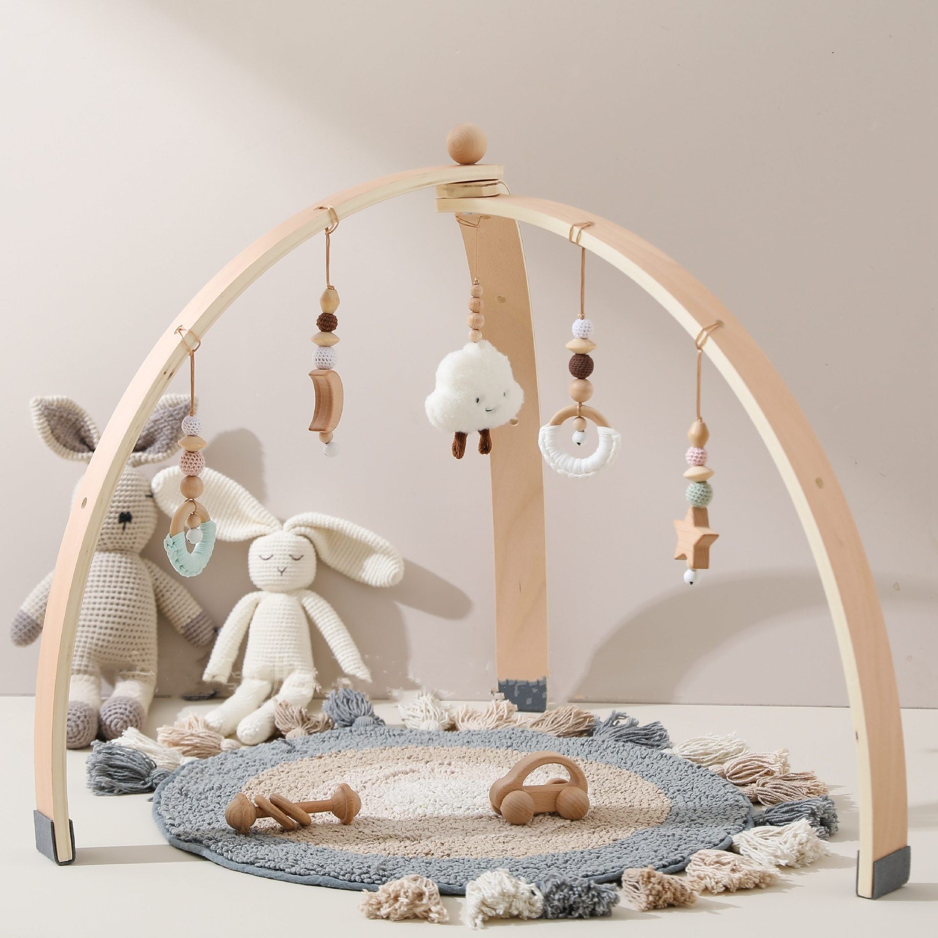 Natural wooden baby activity gym with plush, crochet and beech-bead hanging toys for supervised floor play.